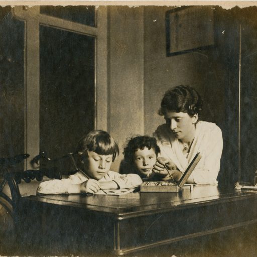 Madre che assiste i figli durante i compiti scolastici, 1920 ca.